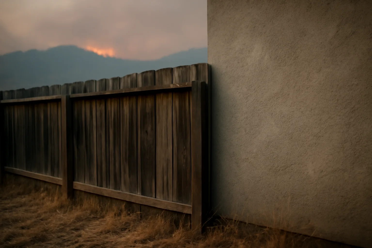 Wood fence touching a house wall, illustrating the real fence fire hazard versus decorative marbles